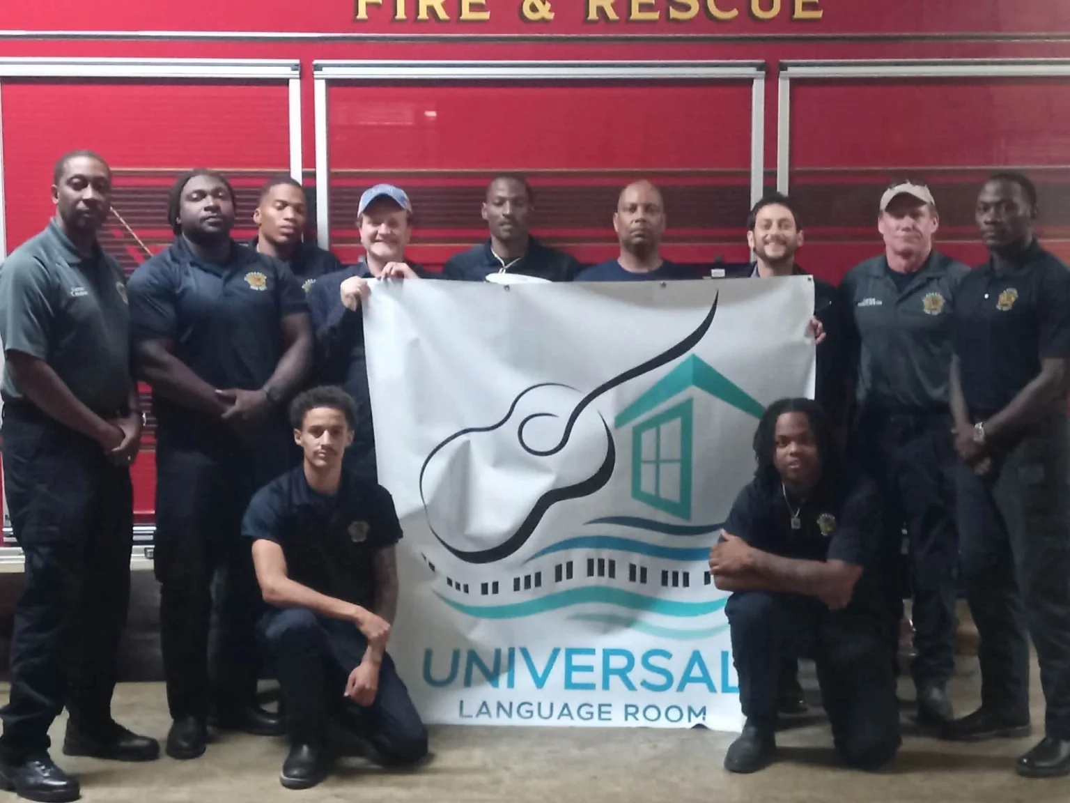 A group of fire and rescue personnel gathered with a Universal Language Room banner.